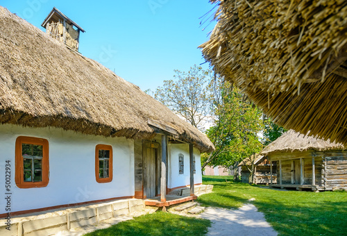A typical antique Ukrainian country house with a thatch roof, in the countryside near Kiev 