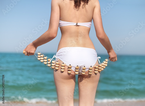 Young slim woman doing self anti cellulite massage on the beach