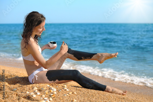 Woman smearing mud mask on the body