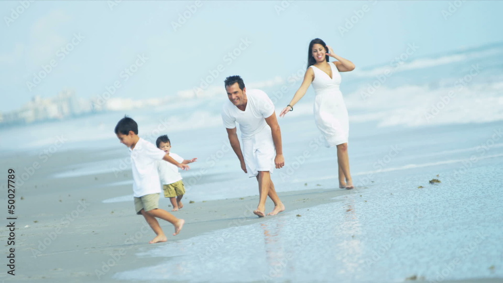 Latin American brothers playing together with parents by ocean Latin American brothers playing together with parents by ocean