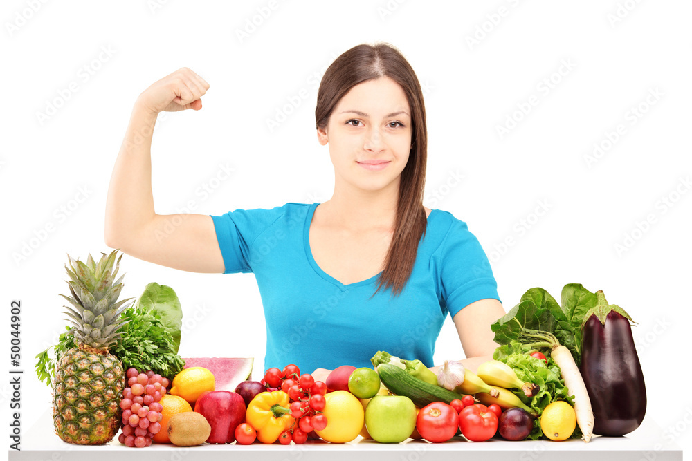 Healthy young female showing her muscle and sitting behind a pil Healthy young female showing her muscle and sitting behind a pil