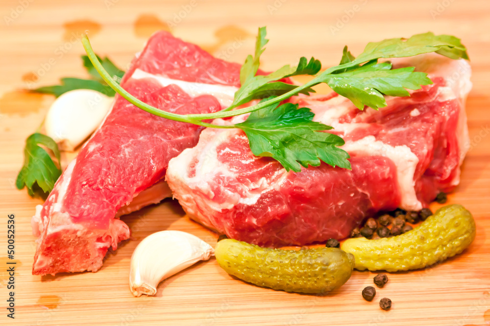 Raw beef with spices and vegetables on the cutting board Raw beef with spices and vegetables on the cutting board