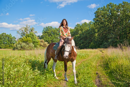 A young girl dressed as an Indian rides a paint horse