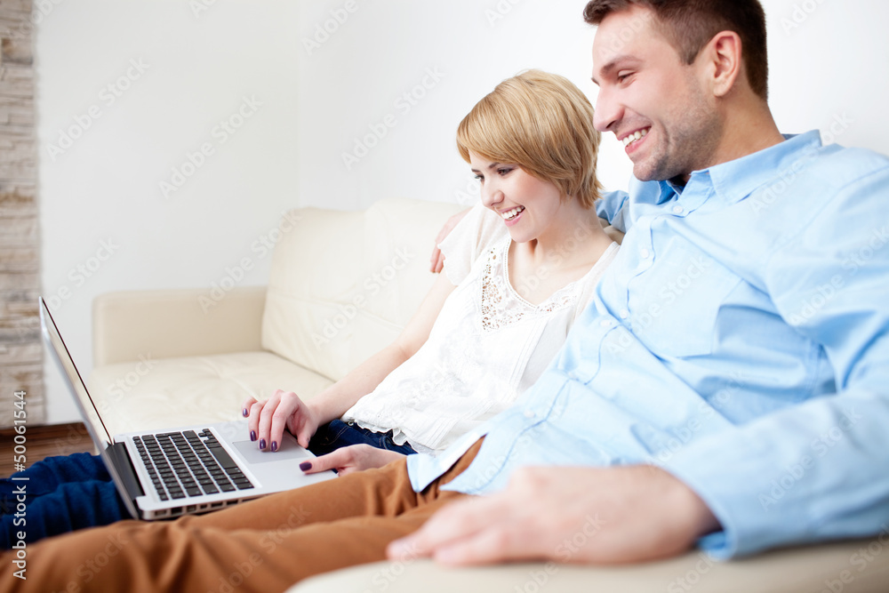 Young couple sitting on couch using laptop Young couple sitting on couch using laptop