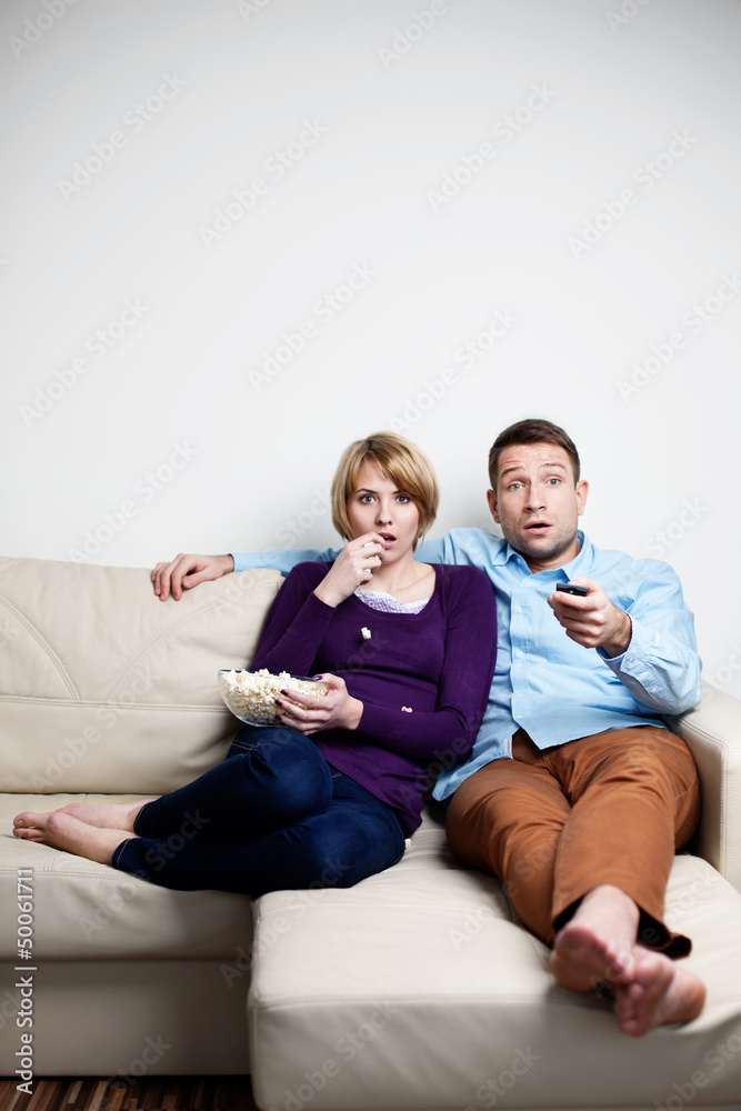 Scared young couple watching tv Scared young couple watching tv