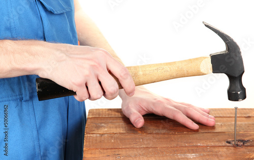 Builder hammering nails into board isolated on white