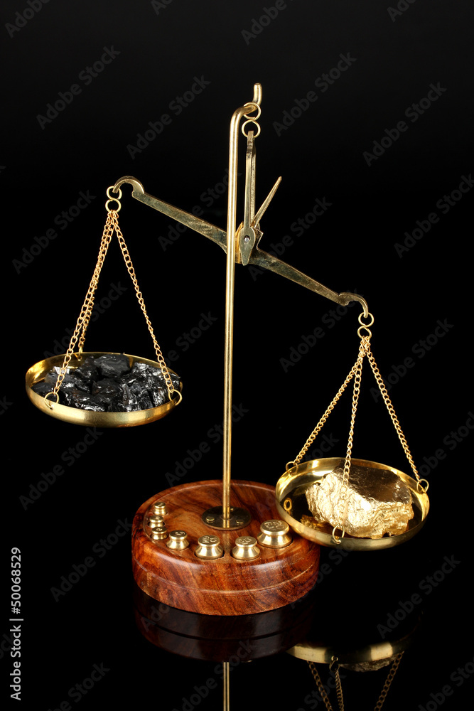 Gold and coal on scales on dark grey background Gold and coal on scales on dark grey background