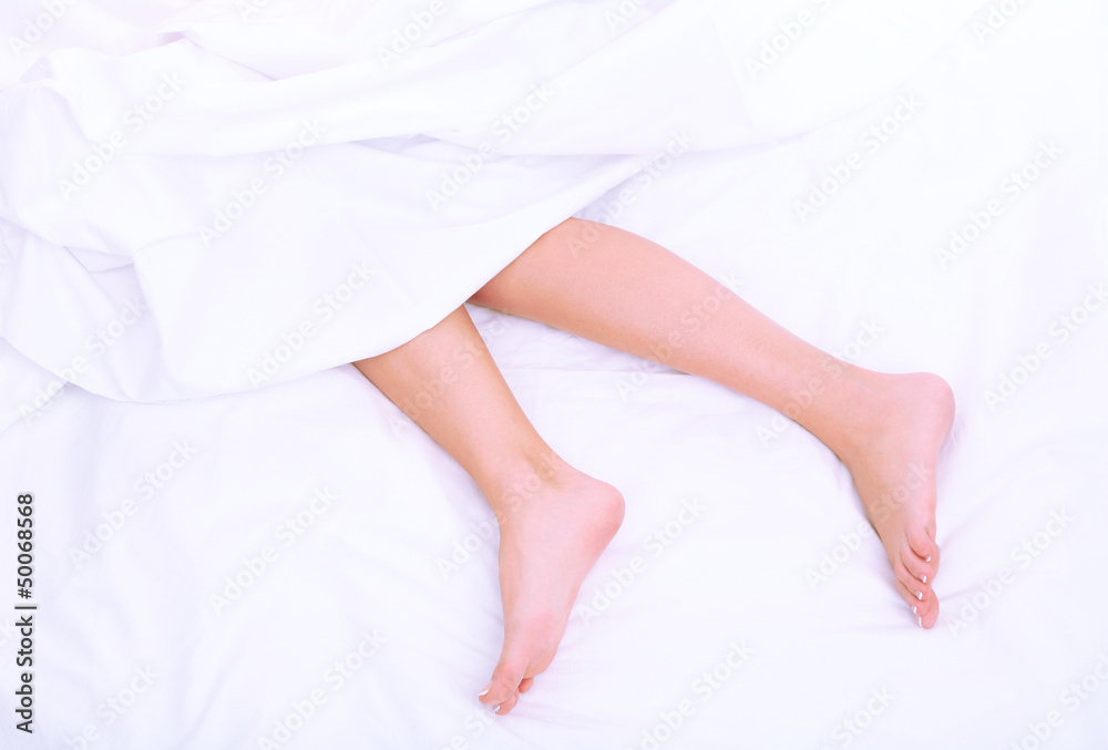 Beautiful feet of a young woman lying in bed close up Beautiful feet of a young woman lying in bed close up