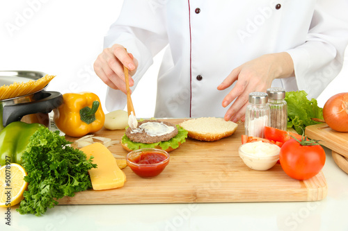 Female hands preparing cheeseburger, isolated on white