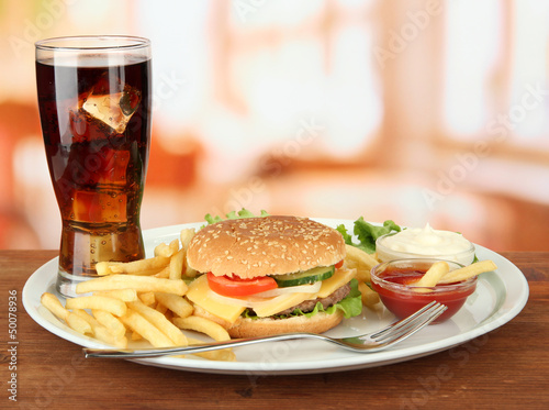 Tasty cheeseburger with fried potatoes and cold drink,
