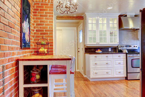 White kitchen with brick wall, hardwood