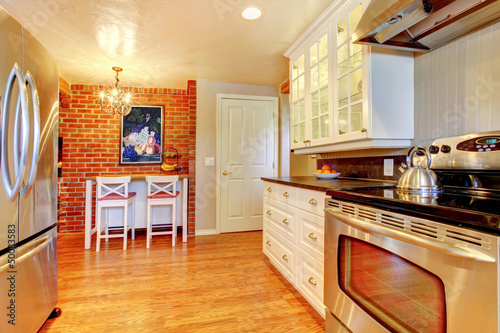 White kitchen with brick wall,