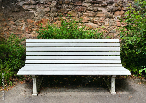 Bild auf Leinwand Wooden bench near a stone wall