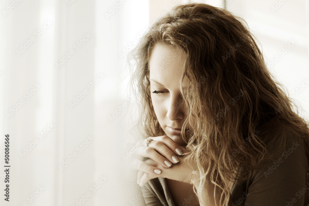 Fototapeta premium Sad woman against a window