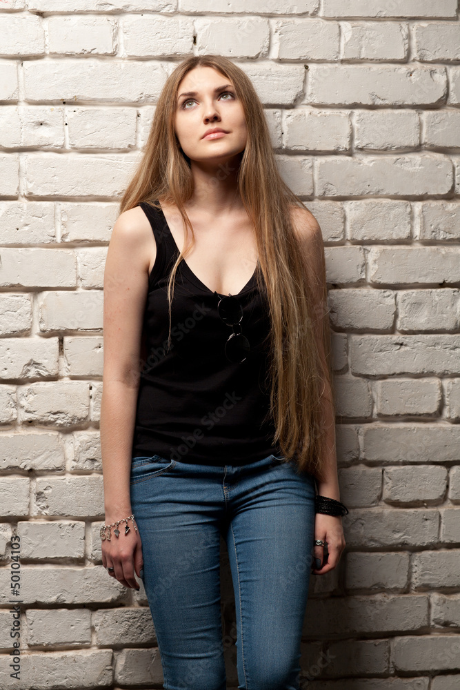Girl posing in studio against a white brick wall Girl posing in studio against a white brick wall