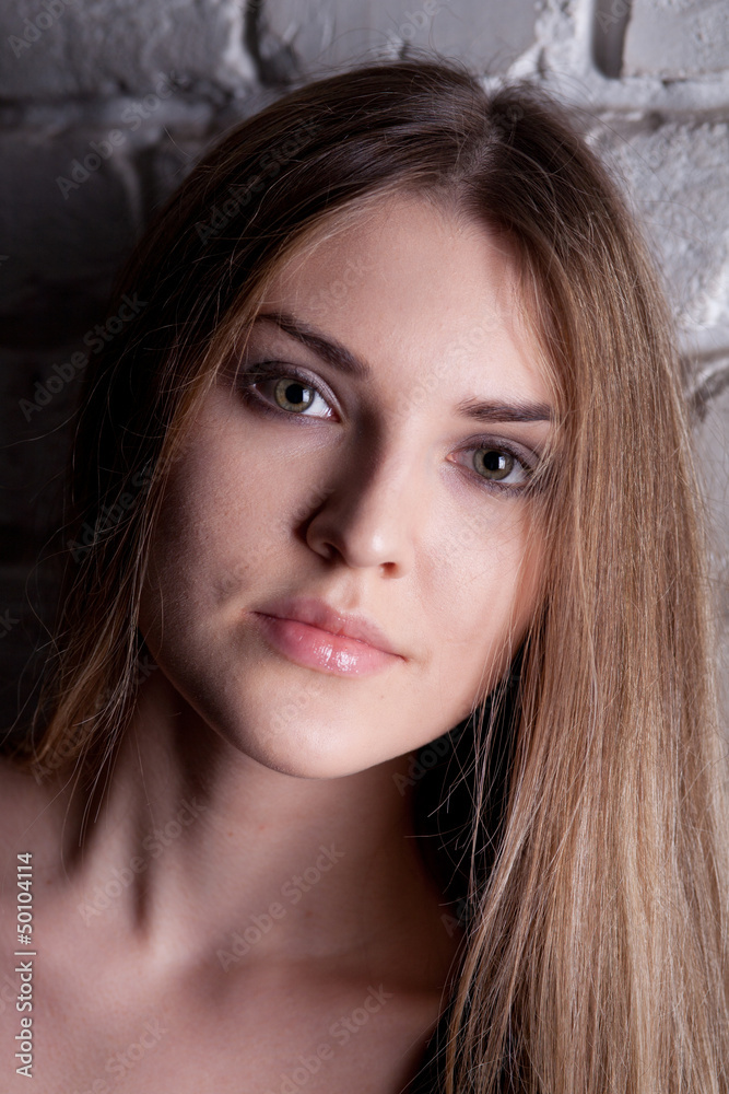 Girl posing in studio against a white brick wall