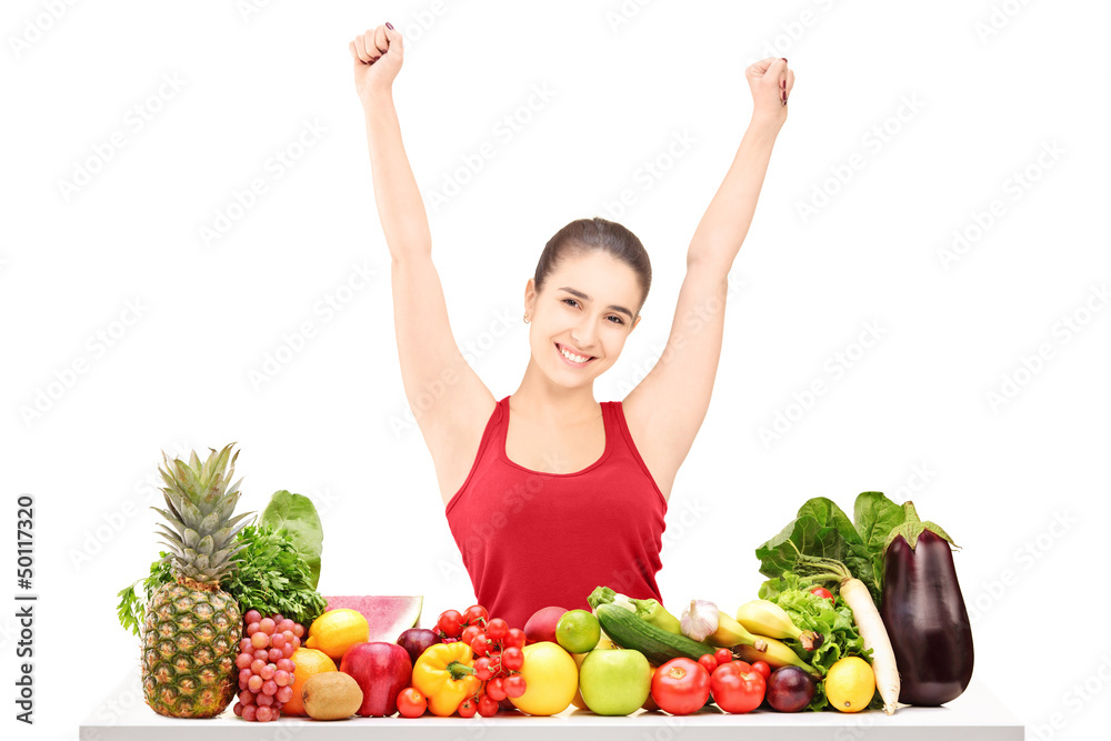 Excited young female gesturing happiness on a table full of frui Excited young female gesturing happiness on a table full of frui