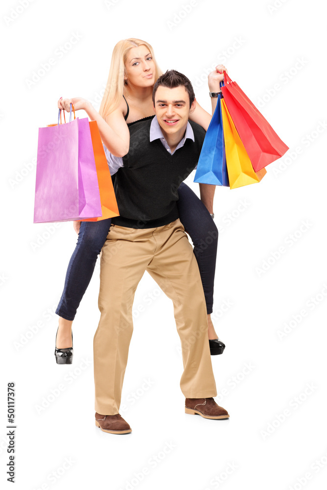 Young man giving a piggyback ride to a woman with shopping bags