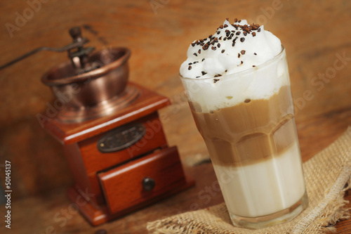 latte macchiato with cocoa powder and coffee beans on wooden tab