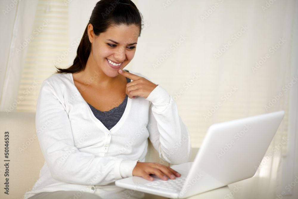 Smiling woman sitting on sofa using her laptop Smiling woman sitting on sofa using her laptop