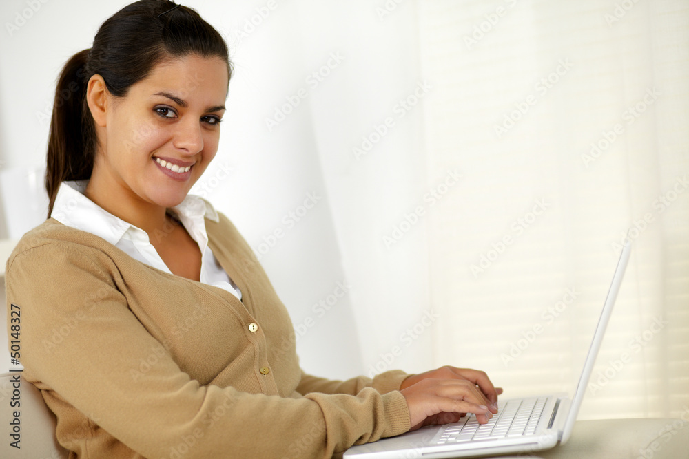 Young woman looking at you while working on laptop Young woman looking at you while working on laptop