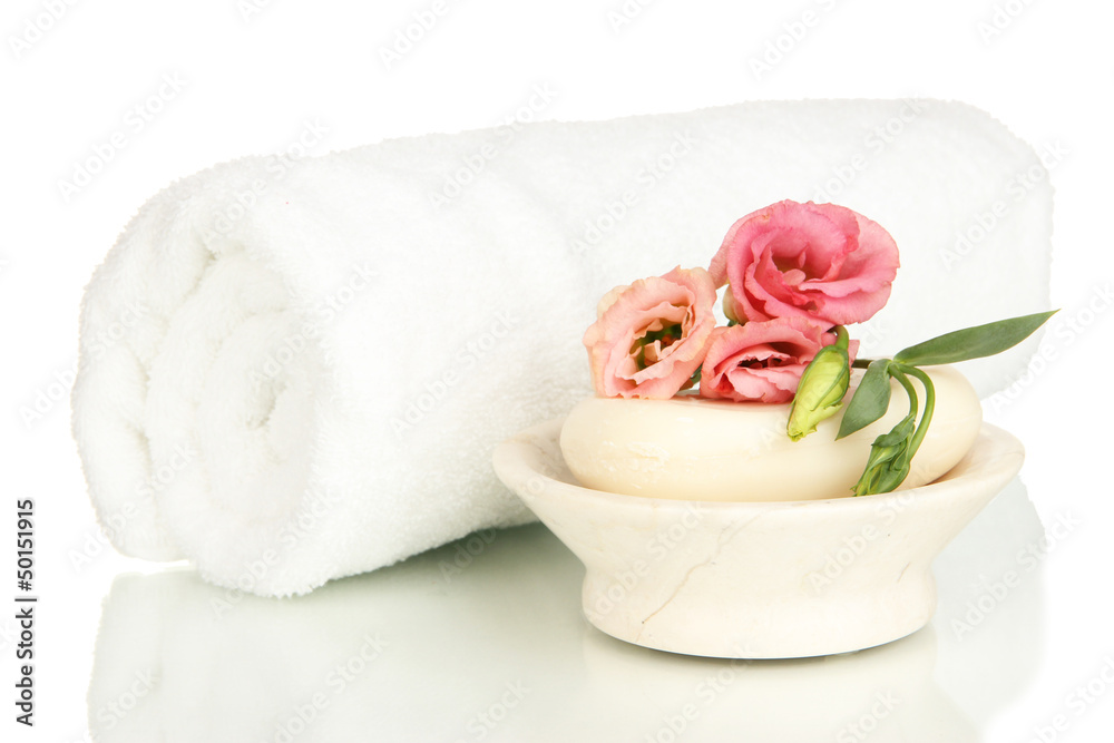 Rolled white towel, soap bar and beautiful flower isolated