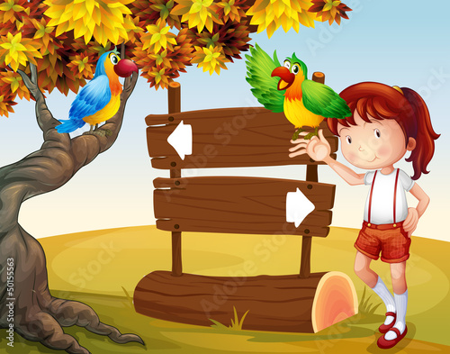 A young girl and her parrots beside the signboard