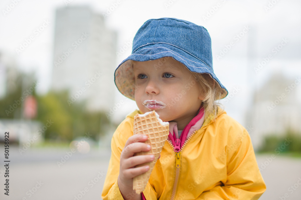 Adorable girl in blue hat eat ice cream on street Adorable girl in blue hat eat ice cream on street