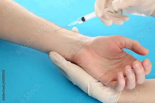 Doctor holding syringe with a vaccine in the patient hand 
