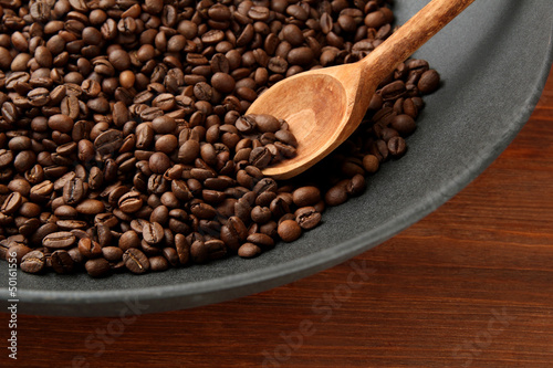 Black wok pan with coffee beans on wooden table  close up
