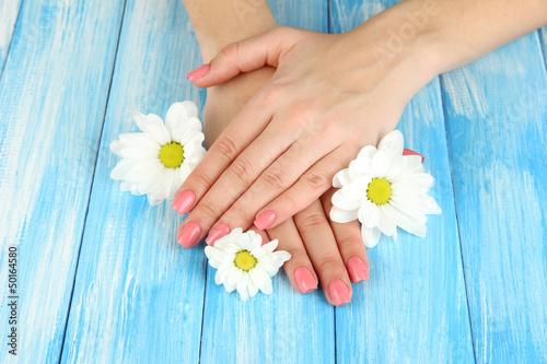 Woman hands with pink manicure and flowers, on color background