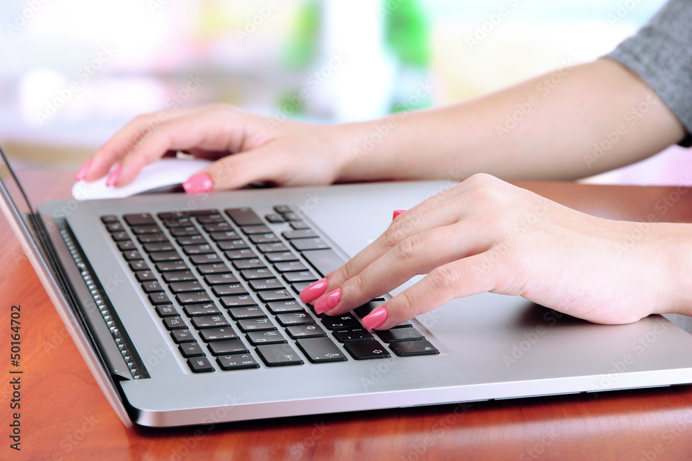 Female hands writing on laptop, on bright background Female hands writing on laptop, on bright background