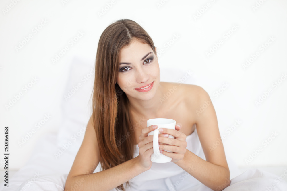 Beautiful smiling young woman in bed with cup of coffee Beautiful smiling young woman in bed with cup of coffee