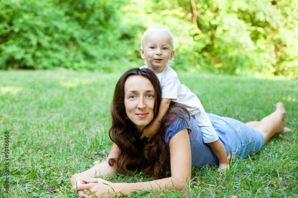 Fototapeta premium Portrait of a mother lying on the lawn with her son