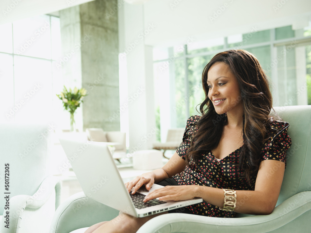 Mixed race businesswoman using laptop in lobby Mixed race businesswoman using laptop in lobby