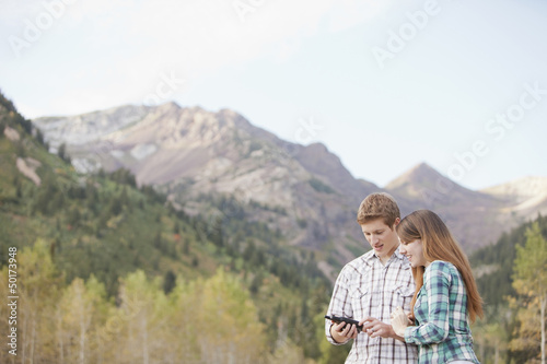 Caucasian couple looking at GPS device in remote area photo