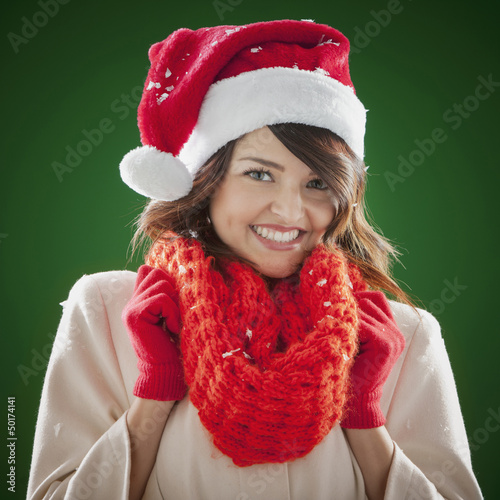 Mixed race woman wearing scarf and Santa hat photo