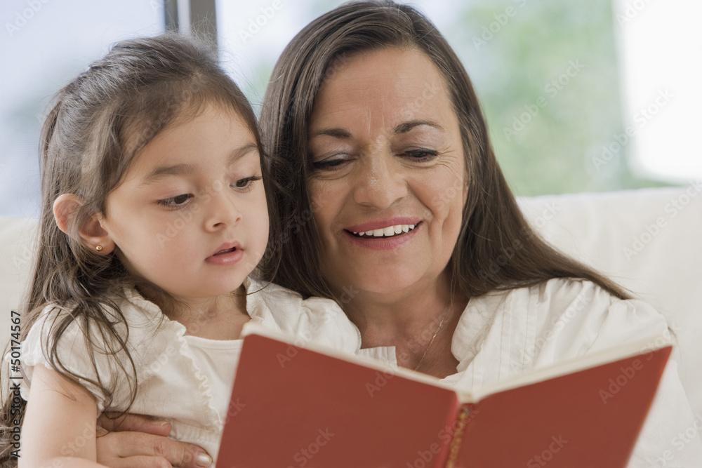 Hispanic grandmother reading to granddaughter Hispanic grandmother reading to granddaughter