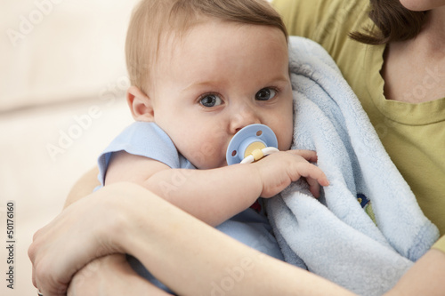 Caucasian baby boy with pacifier in mother's arms photo