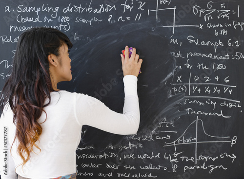 Pacific Islander teacher erasing math from blackboard photo
