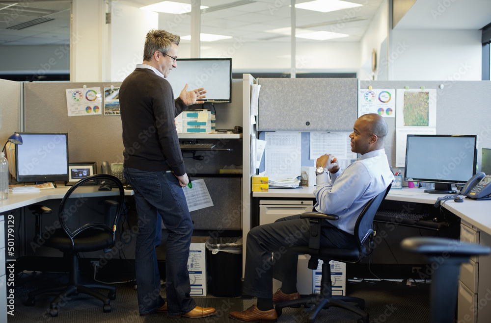 Business people talking in office cubicle Business people talking in office cubicle