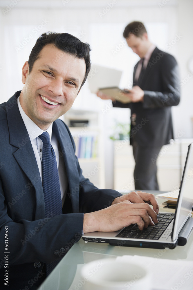 Smiling mixed race businessman using laptop Smiling mixed race businessman using laptop