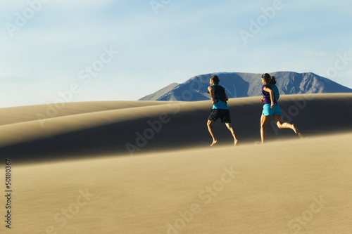 Hispanic couple running on sand dune