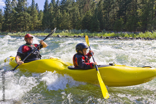 Caucasian father and son kayaking in river photo