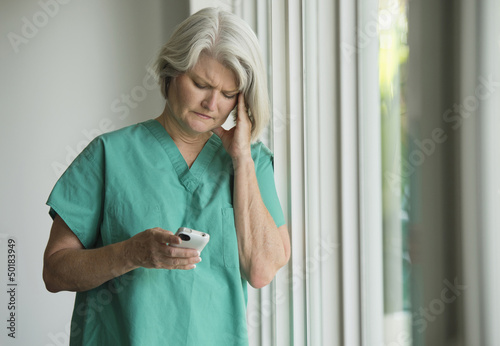 Caucasian surgeon in scrubs using cell phone
