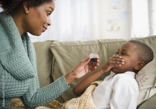 Black mother giving son cough syrup photo