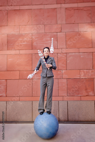 Caucasian businesswoman standing on ball juggling