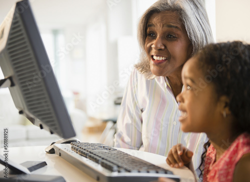 African American grandmother and granddaughter using computer together photo