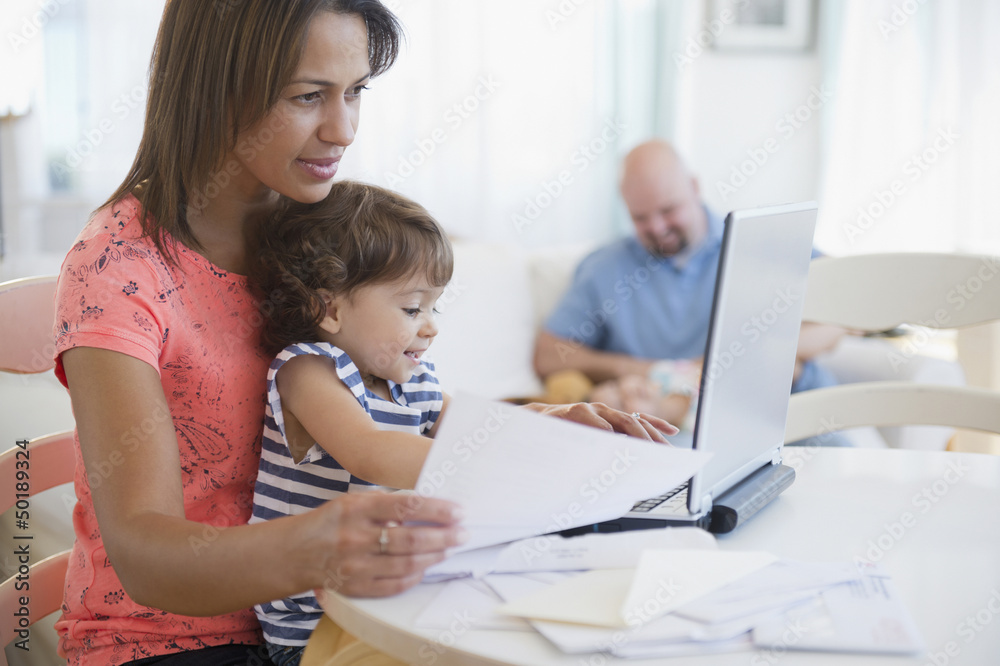 Mother working at computer with child on her lap Mother working at computer with child on her lap
