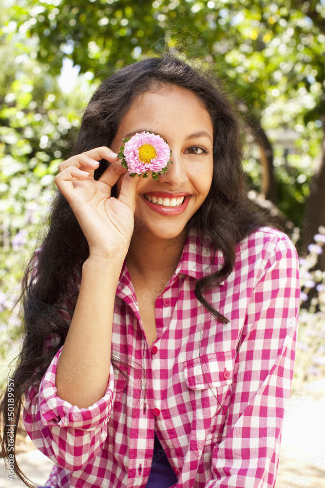 Mixed race teenager holding flower in front of her face Mixed race teenager holding flower in front of her face